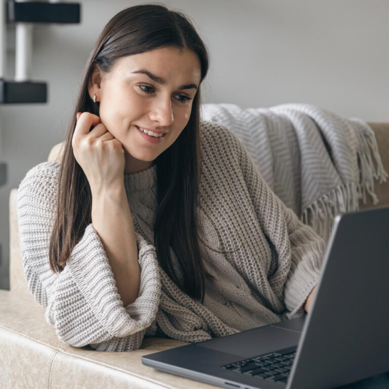 young woman uses laptop while sitting sofa home e1705611484666