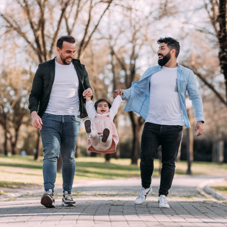 gay couple playing with their little daughter park happy little girl swings from arms her parents