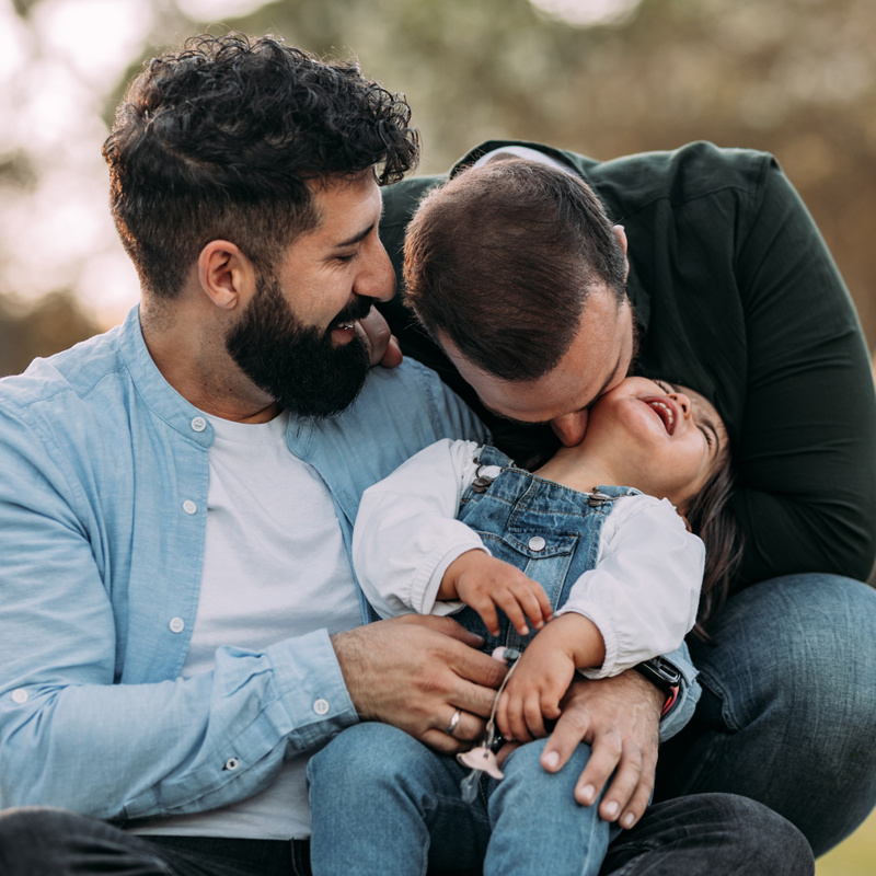 smiling little girl with her parents proud homosexual family concept.png