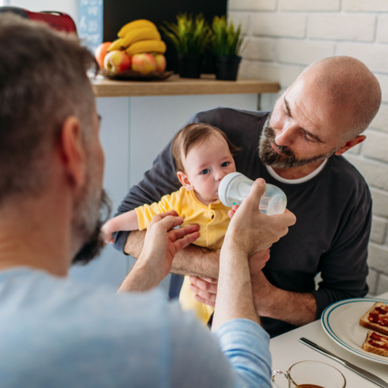 two fathers feeding baby